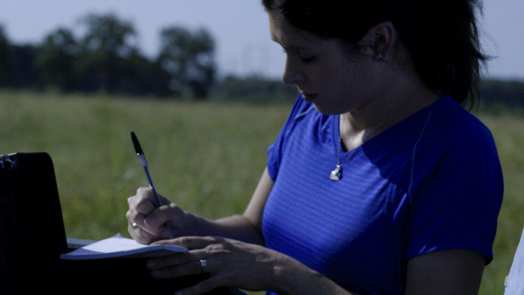 Rancher in field writing